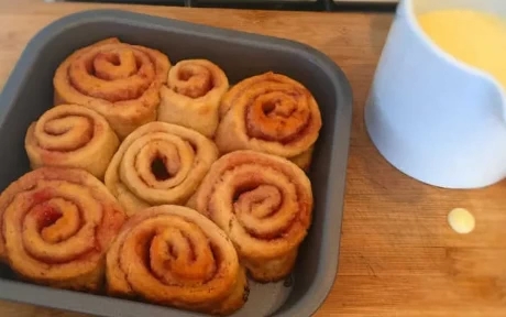 jam roly-poly in a baking tray with a jug of custard