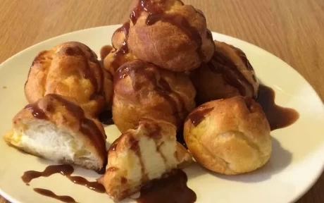 a stack of profiteroles with chocolate sauce